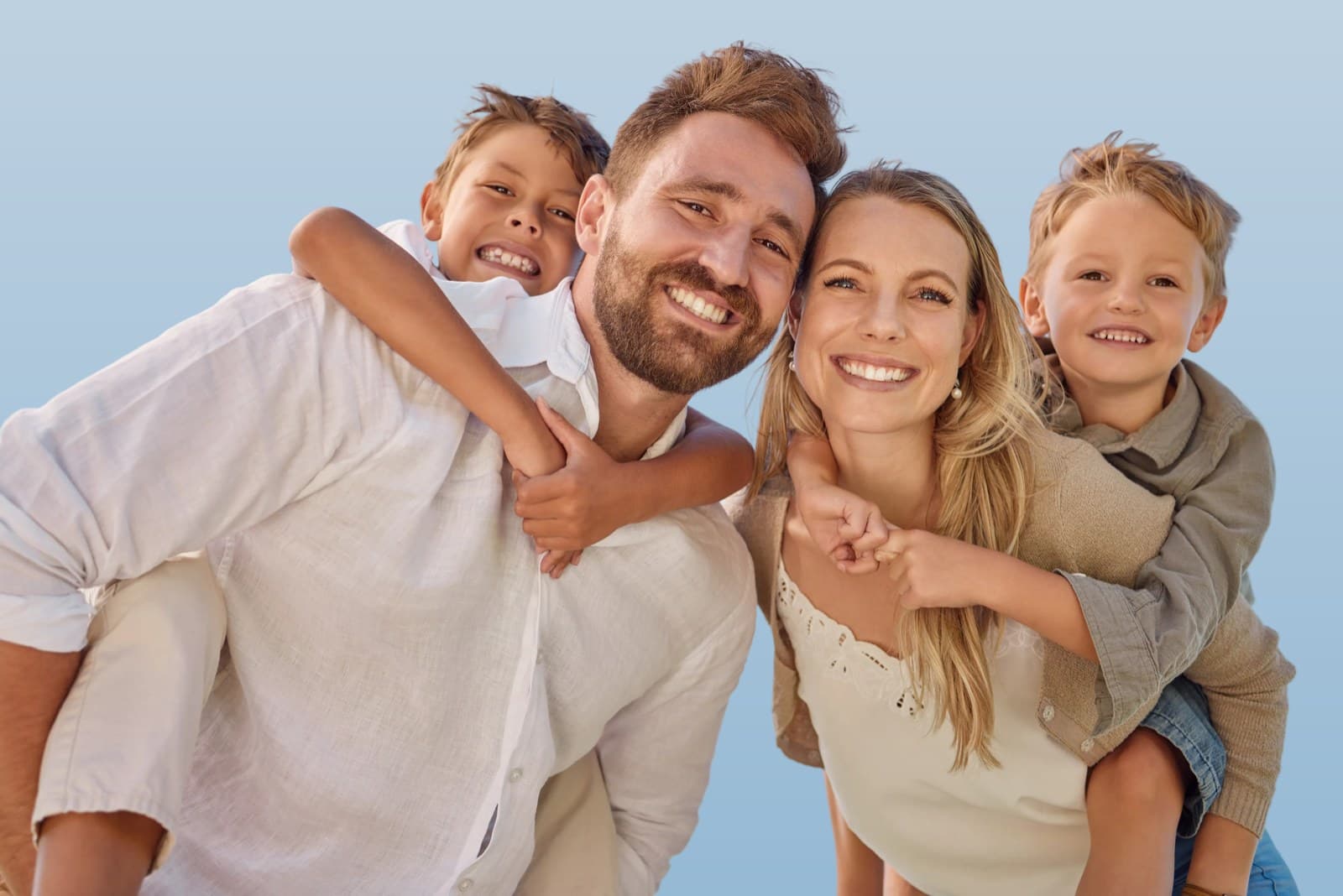 A family piggybacking outdoors under a clear blue sky, representing whole-family care at ANSA Health